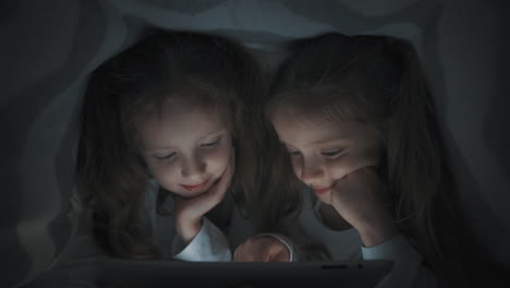 Zwei-Kleine-Mädchen-Benutzen-Ein-Tablet,-Das-Sich-Nachts-Im-Bett-Versteckt