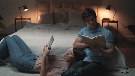 Young-Couple-Sitting-In-Bedroom,-Woman-And-Man-Reading-And-Relaxing,-Sharing-Moments