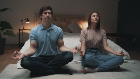 Young-Couple-Meditating,-Woman-And-Man-Sharing-Moments-In-Lotus-Pose-Indoors