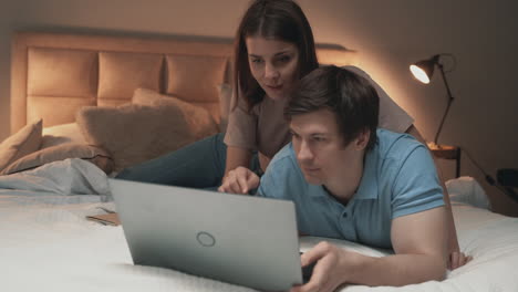 Young-Couple-Using-Laptop-On-Bed,-Woman-And-Man,-Sharing-Moments