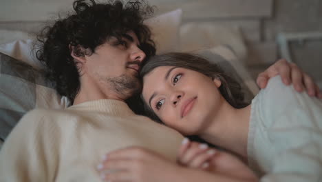 Close-Up-Of-Young-Romantic-Cute-Couple-Lying-In-Bed-Wearing-Winter-Clothes