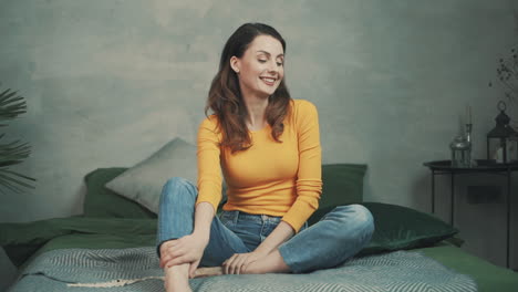 Pretty-Smiling-Woman-Sitting-On-The-Bed-At-Home-And-Laughing
