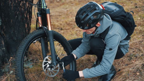 Male-Cyclist-Repairing-A-Mountain-Bike-In-The-Countryside