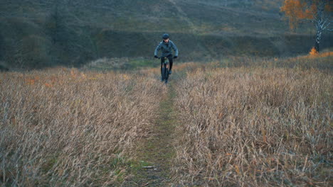 Male-Cyclist-With-Helmet-Riding-A-Mountain-Bike-Down-The-Road-In-The-Countryside-1