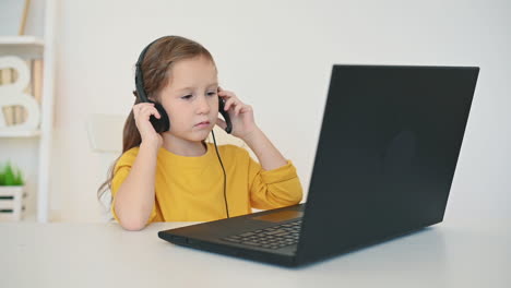 Kleines-Mädchen-Mit-Kopfhörern-Benutzt-Laptop-Zu-Hause