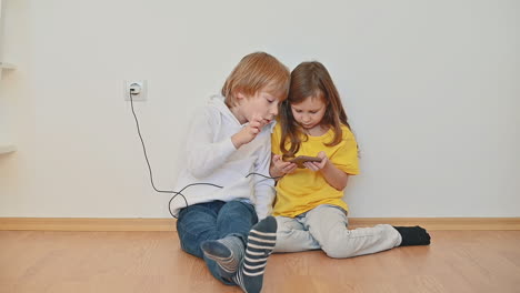 Kleines-Mädchen-Und-Junge-Mit-Einem-Smartphone,-Das-Eine-App-Verwendet-Und-Ein-Online-Videospiel-Spielt