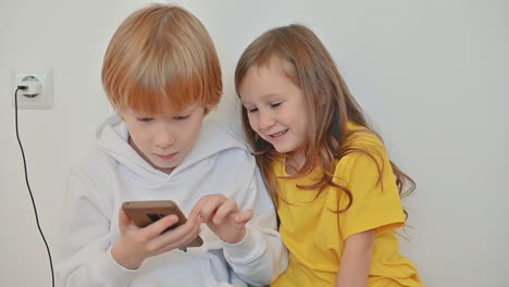 Kleines-Mädchen-Und-Kleiner-Junge-Mit-Einem-Smartphone,-Das-Eine-App-Verwendet-Und-Ein-Online-Videospiel-Spielt-1