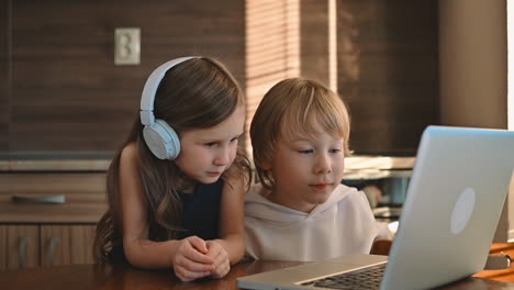 Kleines-Mädchen-Und-Junge,-Die-Einen-Laptop-Mit-Drahtlosen-Kopfhörern-Benutzen-Und-Zu-Hause-Einen-Online-Kurs-Haben