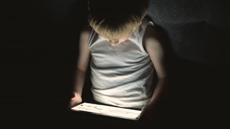 Niño-Usando-Una-Tableta-Viendo-Un-Video-En-Línea-Cubierto-Por-La-Sábana-Por-La-Noche