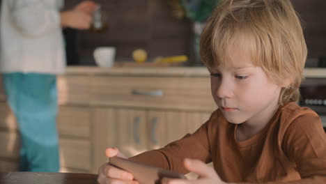 Little-Boy-And-Mother-Watching-Smartphone-At-Home