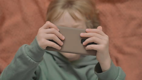 Portrait-Of-Little-Boy-With-A-Smartphone-Watching-An-Online-Video
