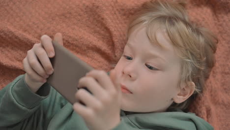 Portrait-Of-Little-Boy-Using-A-Smartphone-Watching-A-Video