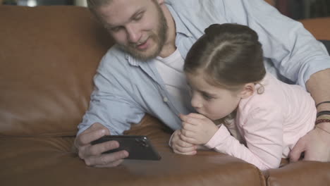 Mann-Und-Tochter-Schauen-Sich-Zu-Hause-Ein-Smartphone-An