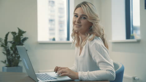Pretty-Young-Blonde-Woman-Working-From-Home-And-Looking-At-Camera-Smiling