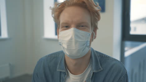 Portrait-Of-Young-Handsome-Redhead-Man-Talking-To-Camera-With-Face-Mask-Indoor