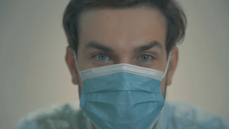 Close-Up-Portrait-Of-Young-Handsome-Man-With-Blue-Eyes-Wearing-A-Face-Mask-And-Looking-At-Camera