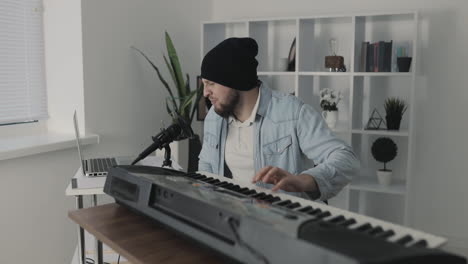 Male-Musician-Singing-And-Playing-Electric-Keyboard-At-Home