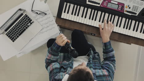 Young-Male-Musician-Creating-Music,-Singing-And-Playing-Electric-Keyboard-At-Home