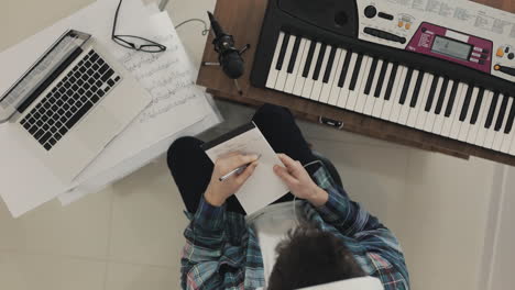 Young-Male-Musician-Creating-Music-And-Taking-Notes-At-Home