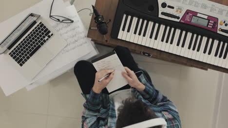 Young-Male-Musician-Creating-Music,-Discarding-Ideas-And-Taking-Notes-At-Home