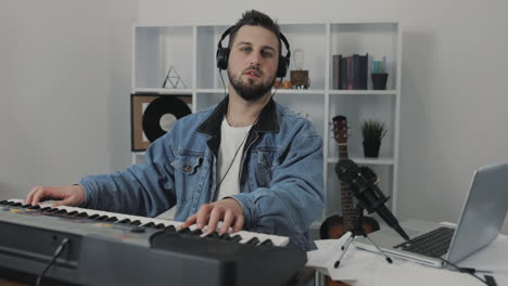Männlicher-Musiker,-Der-Elektrische-Tastatur-Spielt-Und-Zu-Hause-In-Die-Kamera-Schaut