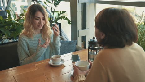 Young-Female-Friends-Talking-And-Having-A-Cup-Of-Tea-And-A-Coffee