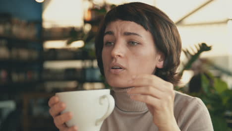Portrait-Of-Female-Talking-To-Her-Friend-And-Having-A-Cup-Of-Coffee