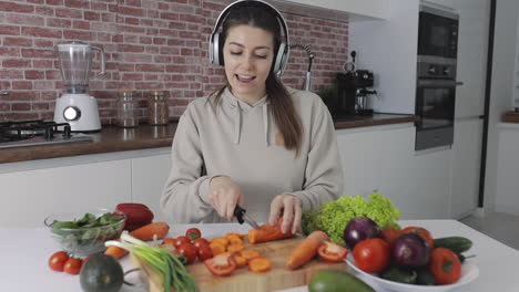 Young-Female-Preparing-A-Vegan-Recipe,-Cutting-Vegetables-And-Listening-To-Music