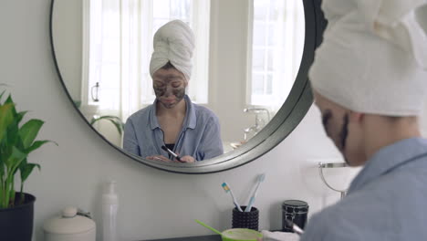 Frau,-Die-Gesichtsmaske-Anwendet-Und-In-Den-Spiegel-Schaut