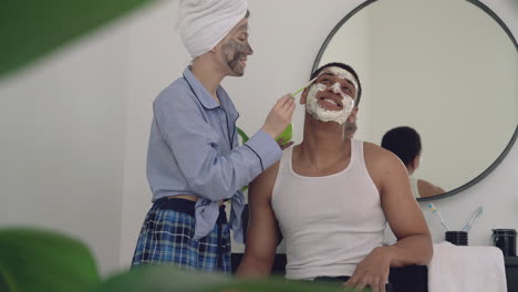 Female-With-Facial-Mask-Applying-Scrub-To-A-Handsome-Black-Man