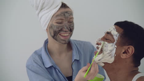 Woman-With-Facial-Mask-Applying-Scrub-To-A-Handsome-Black-Man-1