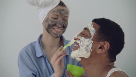 Female-With-Facial-Mask-Applying-Scrub-To-A-Handsome-Black-Man-1