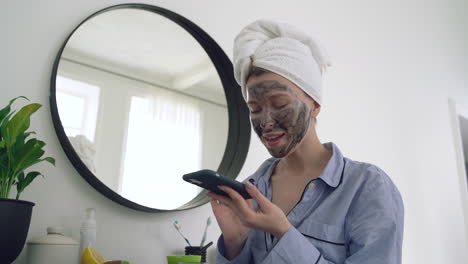 Frau-Mit-Gesichtsmaske,-Die-Ein-Smartphone-Verwendet-Und-Spricht