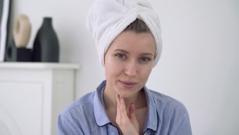 Portrait-Of-Young-Female-Applying-Moisturizer-And-Looking-To-Camera
