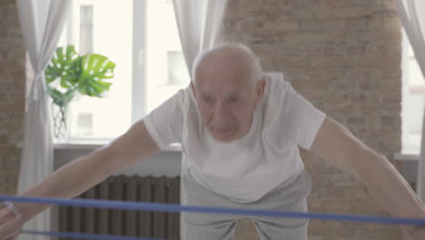 Old-Man-Using-A-Stretching-Band-And-Exercising-At-Home-1