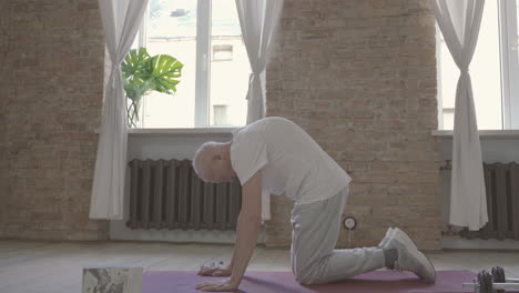 Alter-Mann,-Der-Sich-Zu-Hause-Auf-Yogamatte-Dehnt-Und-Trainiert