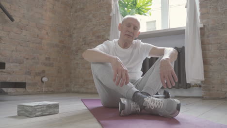Alter-Mann,-Der-Zu-Hause-Auf-Yogamatte-Sitzt