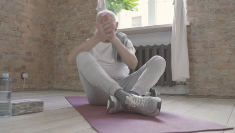 Alter-Mann,-Der-Zu-Hause-Auf-Yogamatte-Ruht-Und-Sitzt