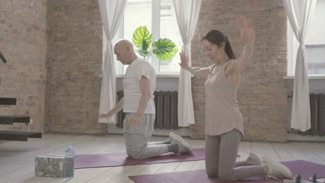 Old-Male-And-Female-Doing-Exercises-On-Yoga-Mat-At-Home