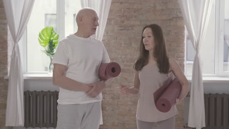 Old-Male-And-Female-Talking-With-A-Yoga-Mat-At-Home