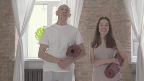 Old-Male-And-Female-With-A-Yoga-Mat-Looking-At-Camera