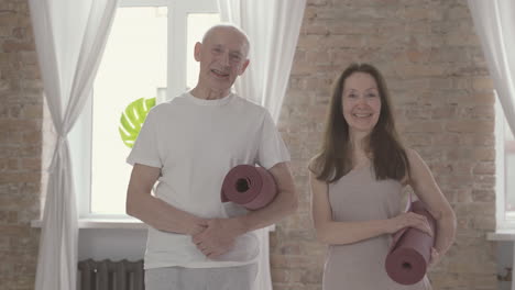 Old-Female-And-Male-With-A-Yoga-Mat-Looking-At-Camera
