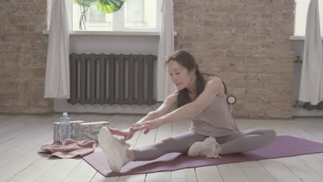 Alte-Frau,-Die-Sich-Zu-Hause-Auf-Yogamatte-Dehnt-Und-Trainiert