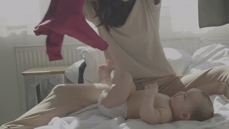 Happy-Mom-Undressing-Her-Cute-Baby-At-Home