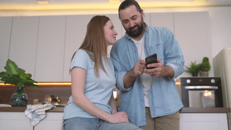 Bearded-Man-Showing-Mobile-Phone-Photos-To-An-Attractive-Woman