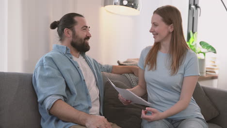 Bearded-Man-And-Beautiful-Woman-Have-A-Relaxed-Conversation-Sitting-On-The-Sofa