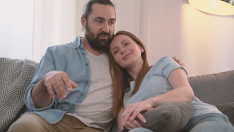 Bearded-Man-Converses-With-His-Partner,-An-Attractive-Woman,-Who-Rests-Her-Head-On-His-Shoulder