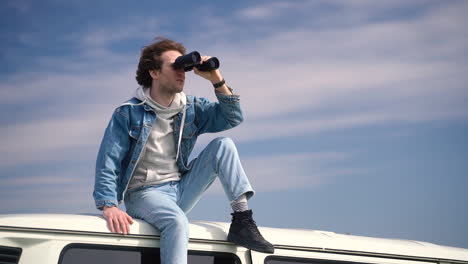 Young-Boy-Looks-Around-With-A-Pair-Of-Binoculars-On-The-Roof-Of-A-Caravan