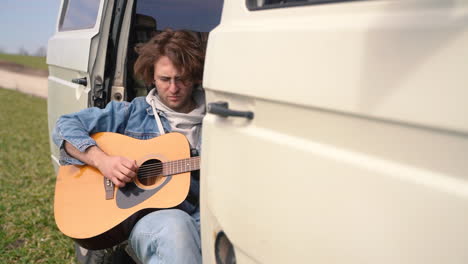 Ein-Junger-Mann-Mit-Brille-Spielt-Hinten-In-Einem-Wohnwagen-Gitarre