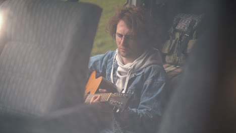 A-Young-Guy-With-Glasses-Plays-The-Guitar-In-The-Back-Of-A-Caravan-1